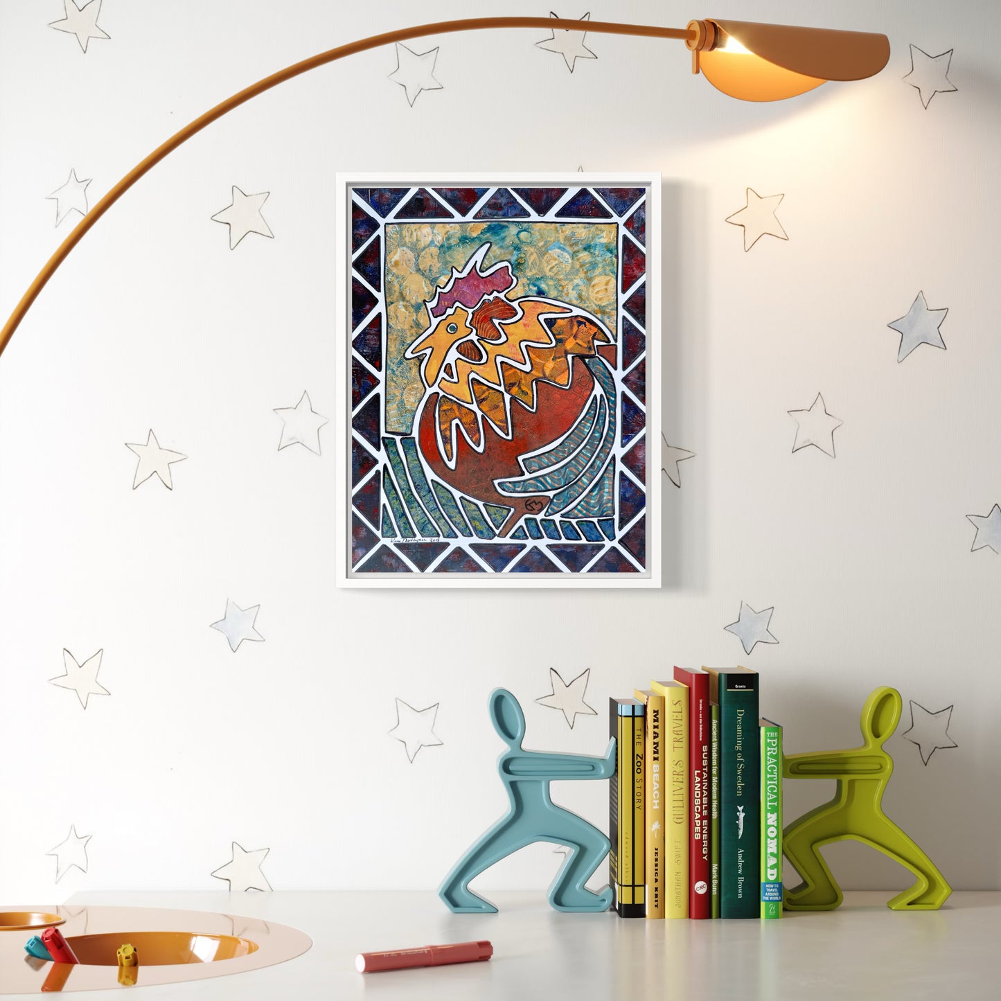 Framed artwork of abstract rooster with patterned boarder on a wall with decorative bookends and books below.