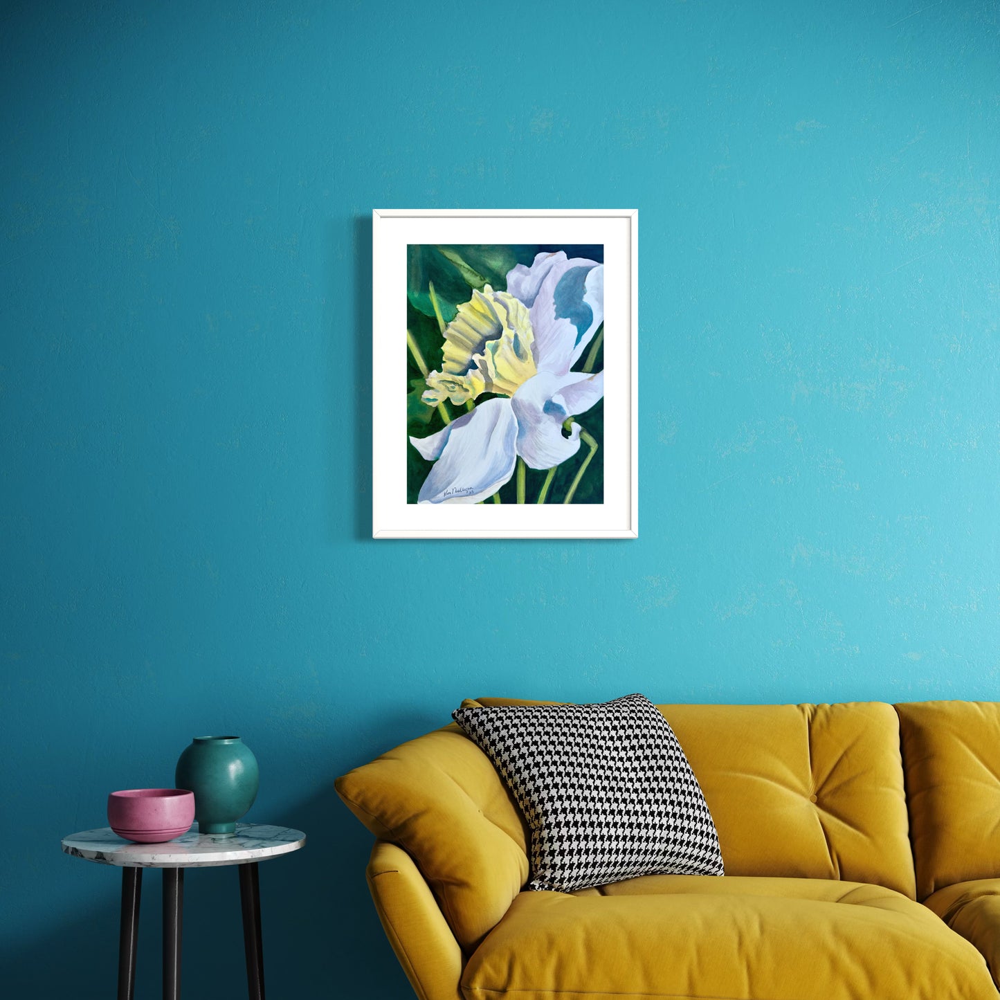Framed watercolor artwork of a yellow and white daffodil flower on a blue wall above a yellow sofa.