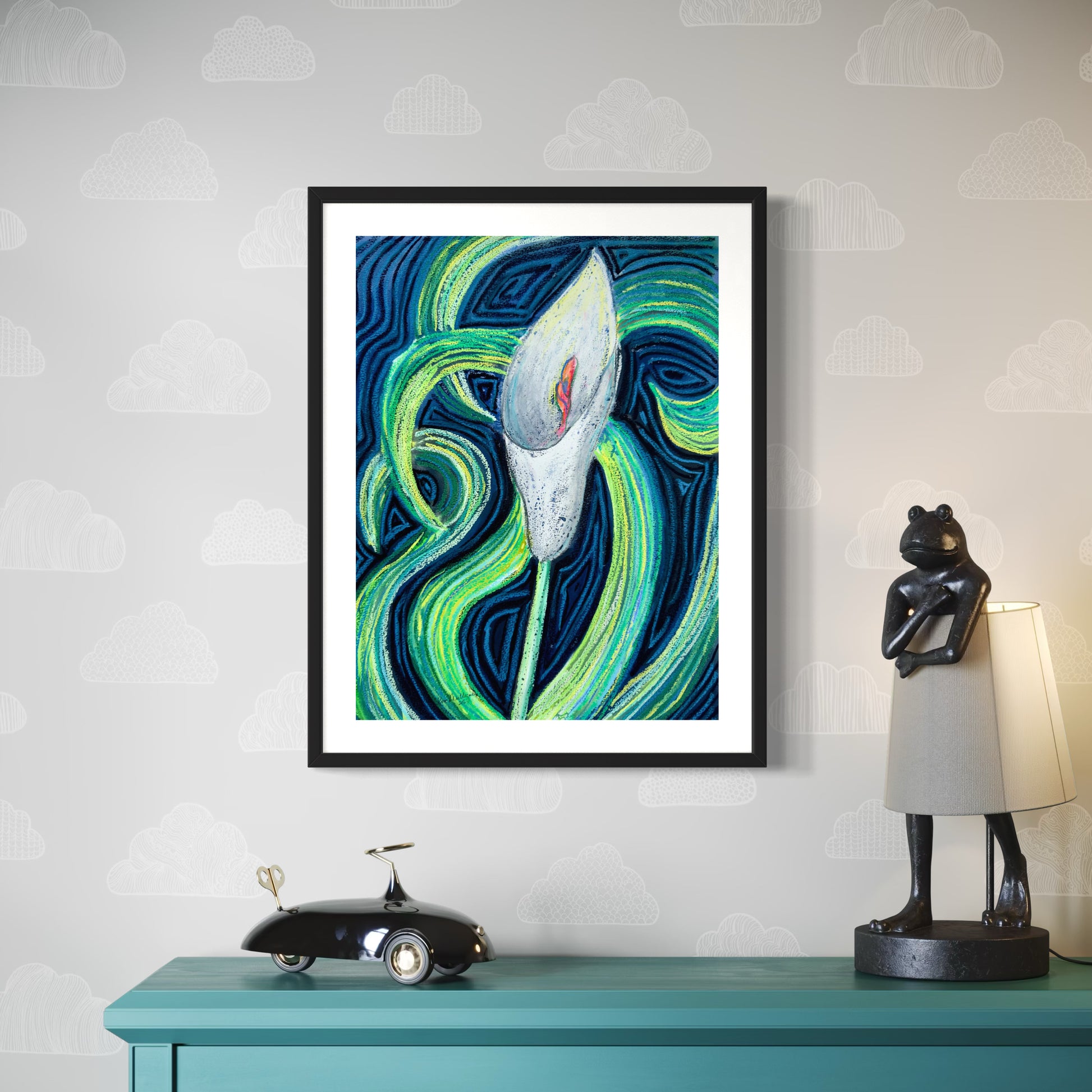 Framed abstract artwork of a cala lily flower on a wall above a teal console table with decorative items.