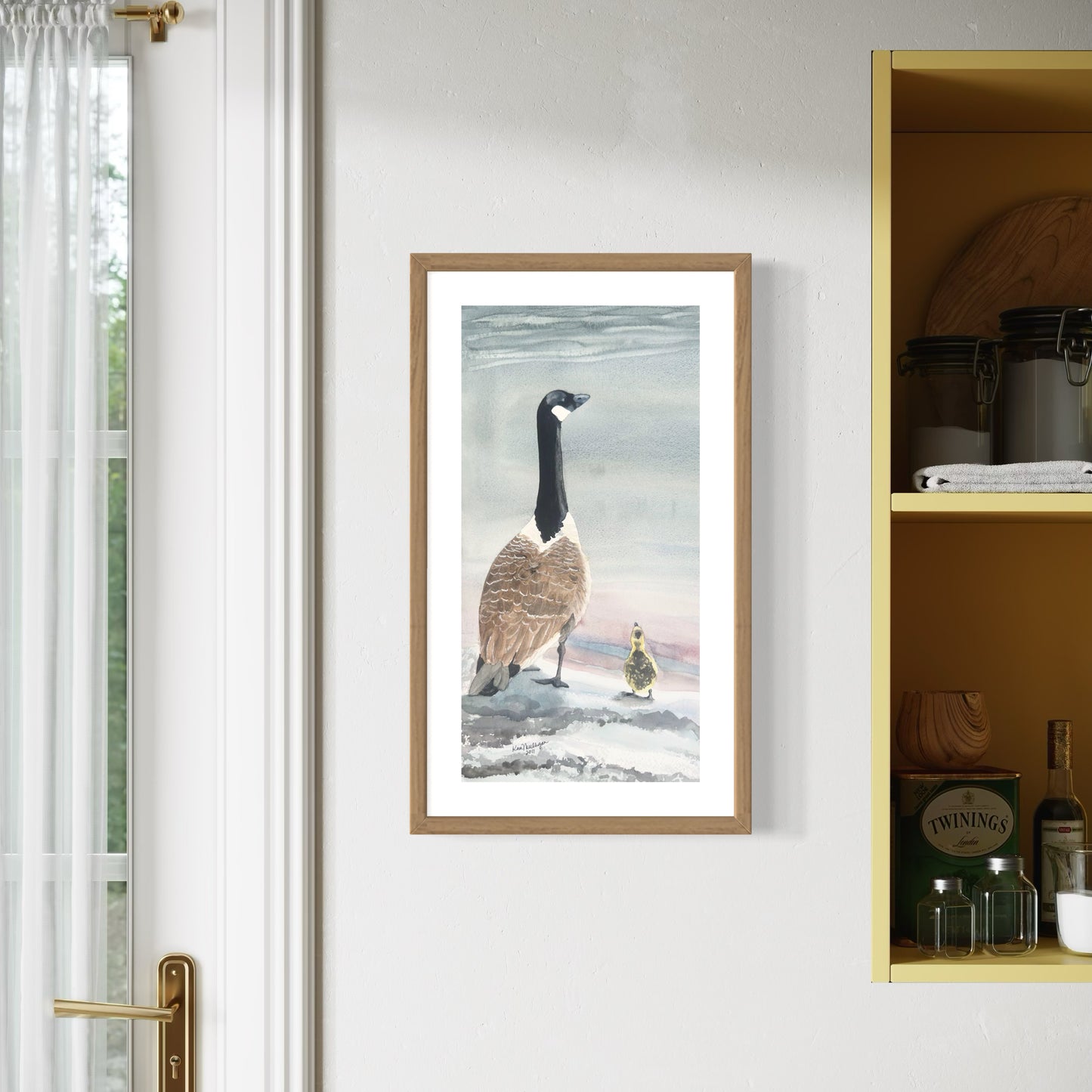 Framed Watercolor painting of a Canada goose and gosling looking out over the water from a beach