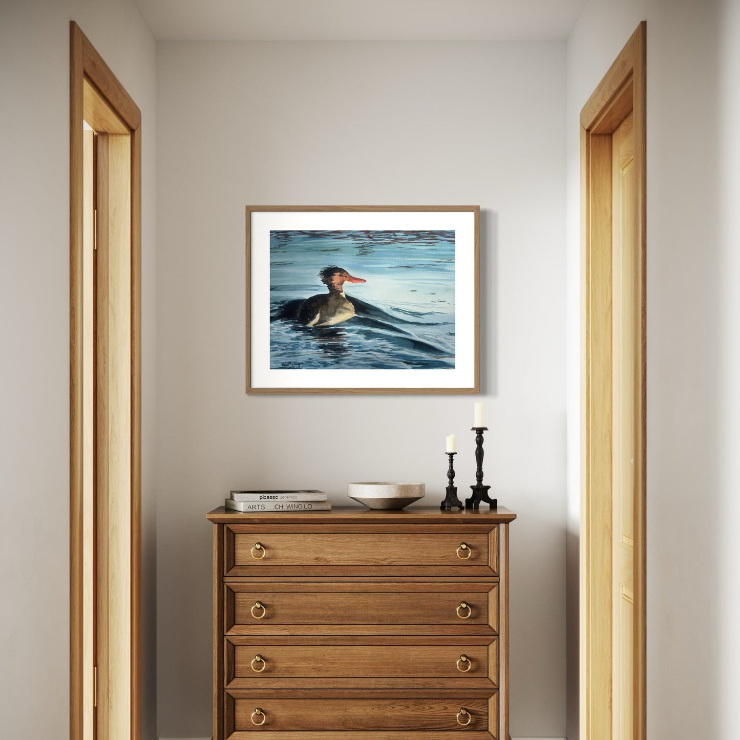 Framed watercolor artwork of a common merganser on water.