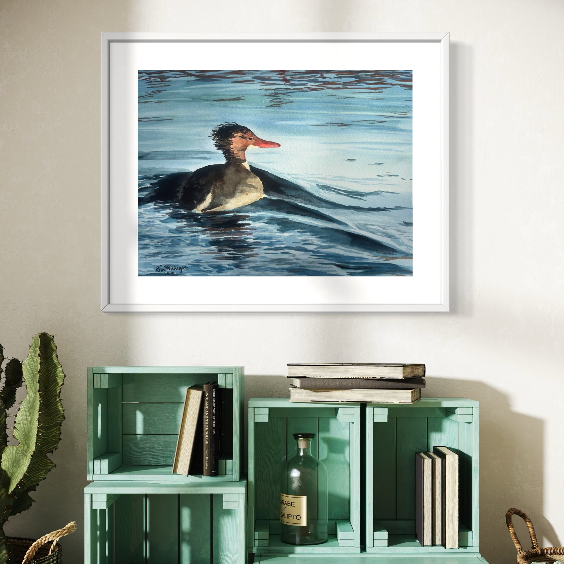 Framed watercolor artwork of a common merganser on water.