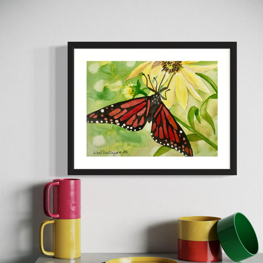 Framed watercolor painting of a black and orange monarch butterfly on yellow flower with green background.