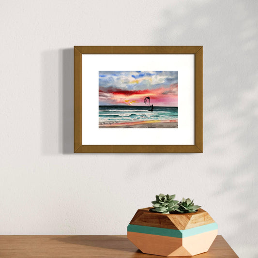 Framed watercolor artwork of a sunset beach scene with a kite surfer.