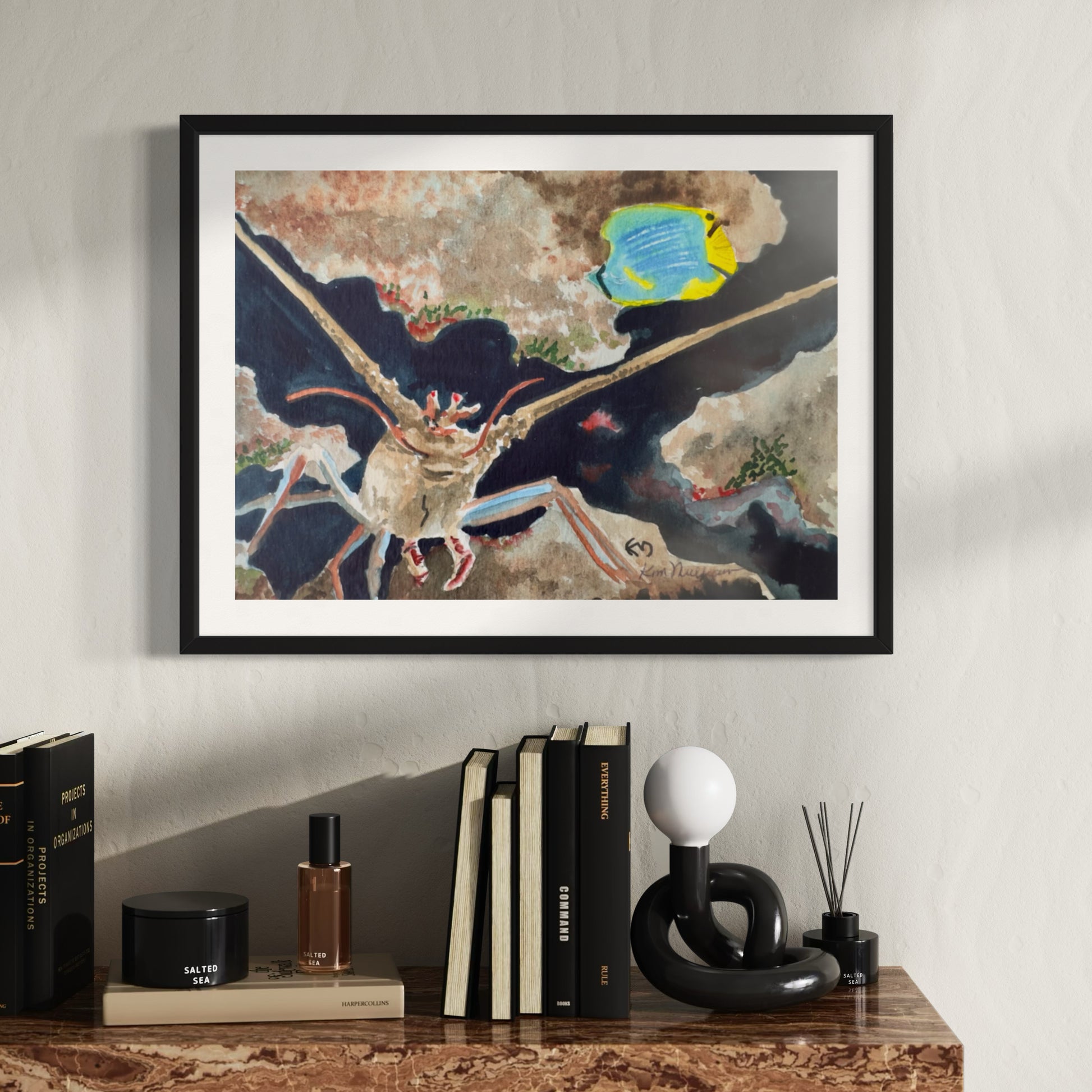 Framed artwork of a lobster amoung rocks with a blue and yellow tropical fish.