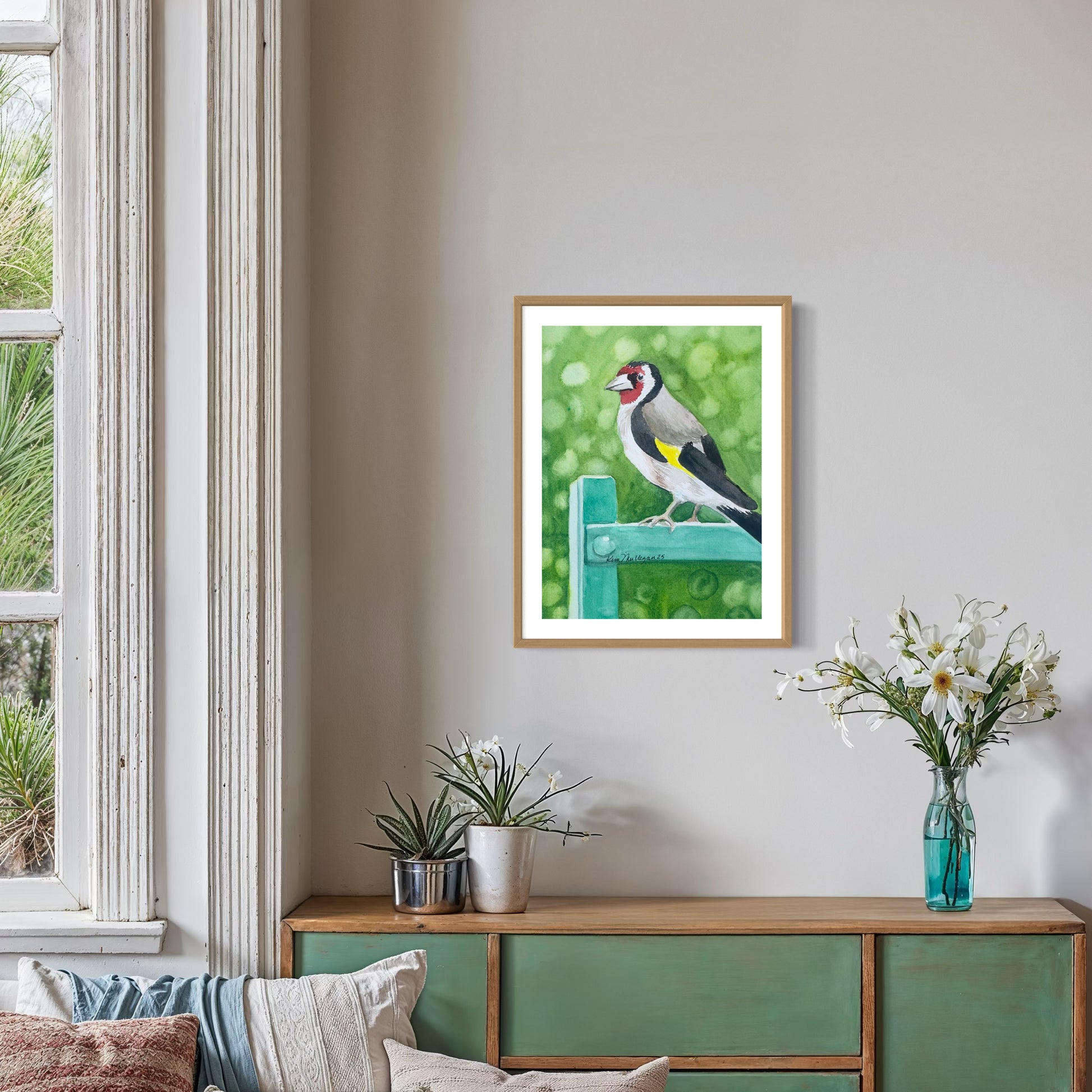 Framed watercolor painting of a bird on a green background in a living room setting.