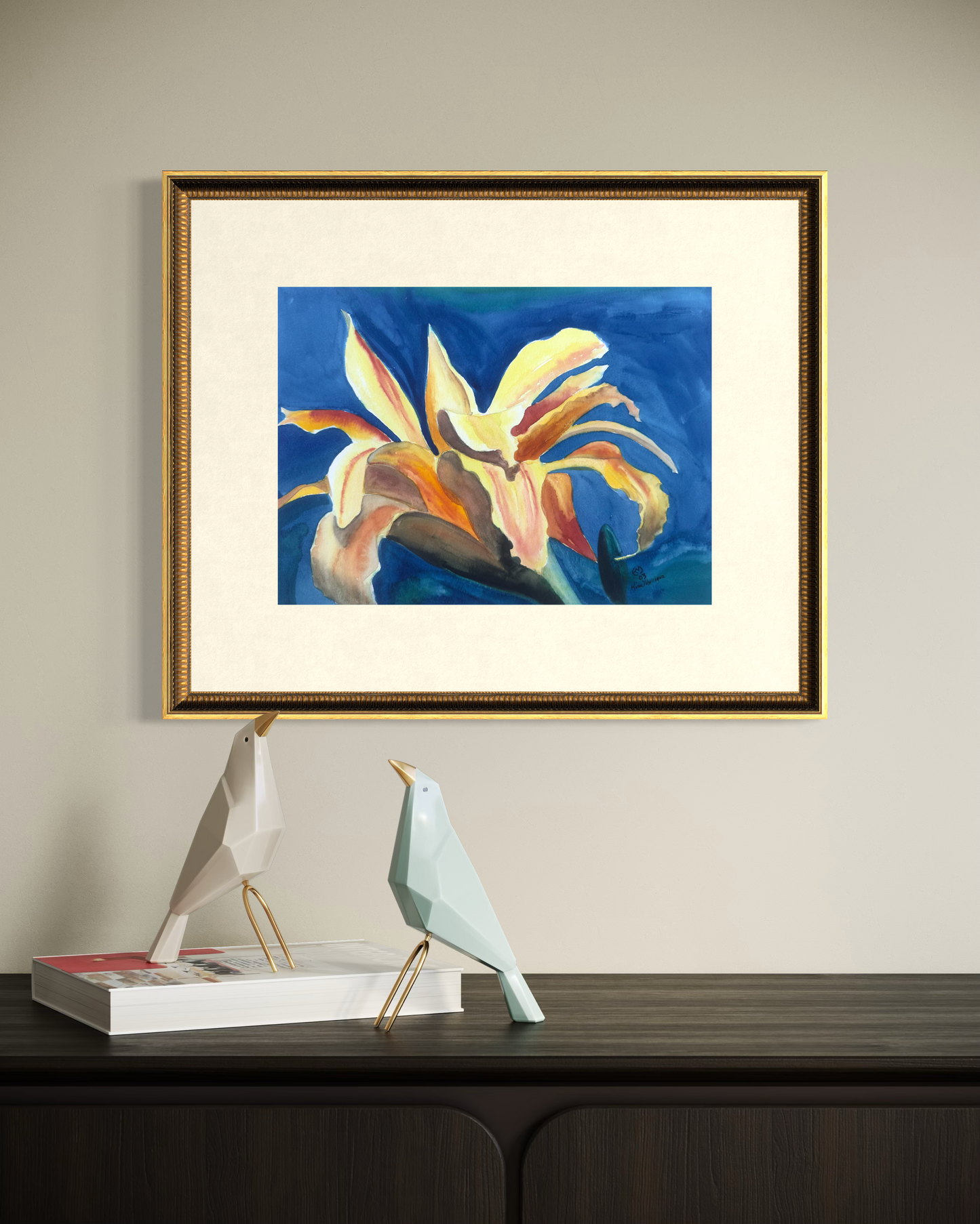 Framed floral watercolor painting of a flower on a wall above a wooden surface with decorative items.