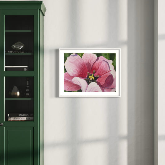 Framed artwork of a close up pink tulip flower on a wall next to a green cabinet.