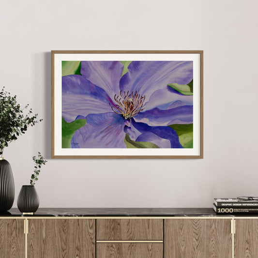 Framed watercolor artwork of a purple clematis flower on a wall above a wooden cabinet.