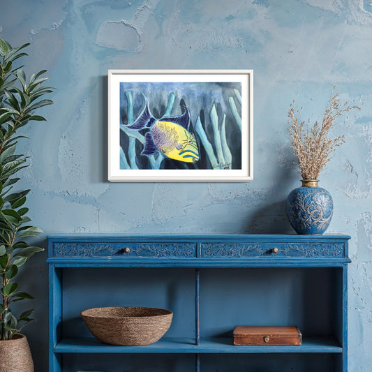 Framed watercolor artwork of queen trigger fish on a blue wall above a blue shelf with decorative items.