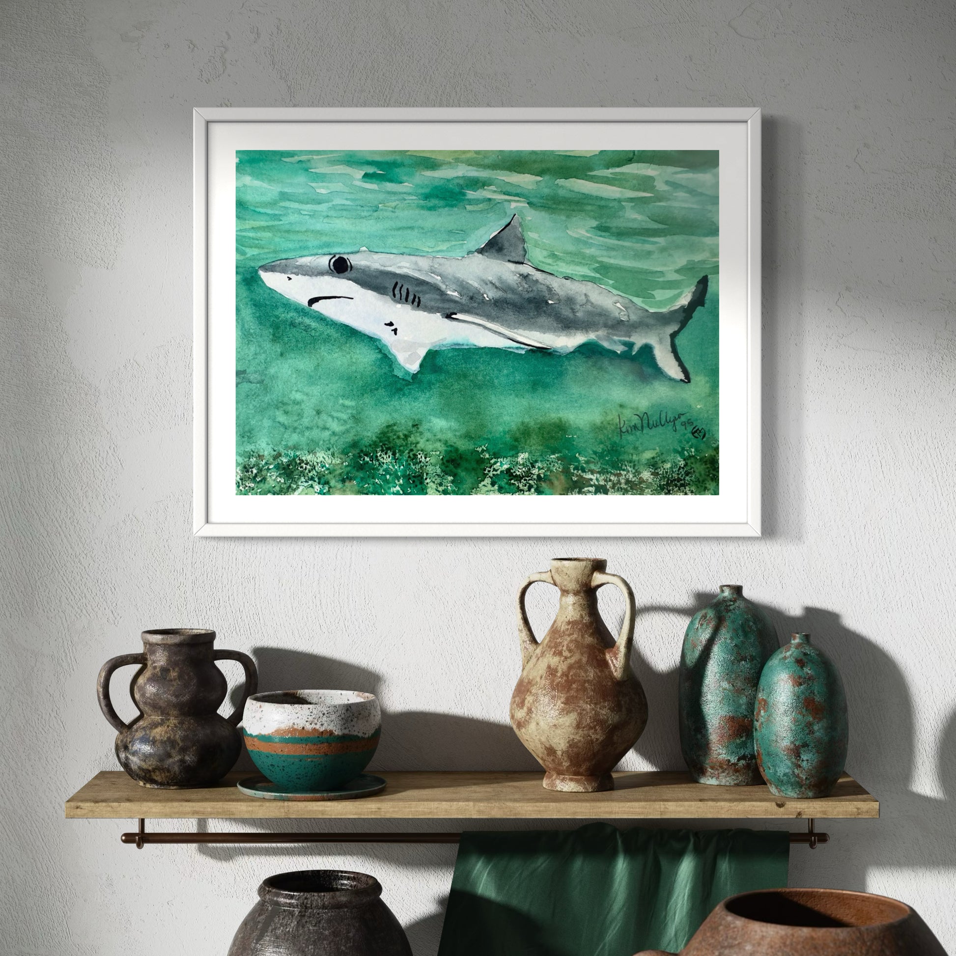Framed artwork of a shark on a wall above a shelf with decorative vases.