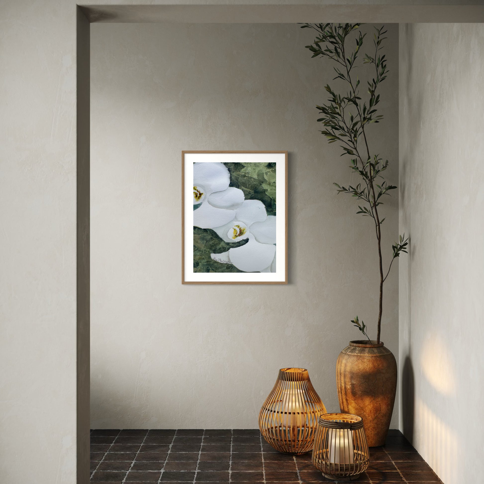 Framed artwork of white orchid flowers on a wall with decorative vases and a plant on a tiled floor.