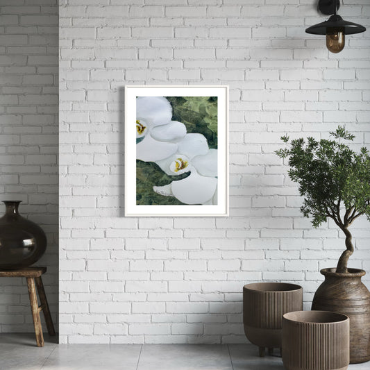 Framed artwork of white orchid flowers on a white brick wall with decorative vases and plants.