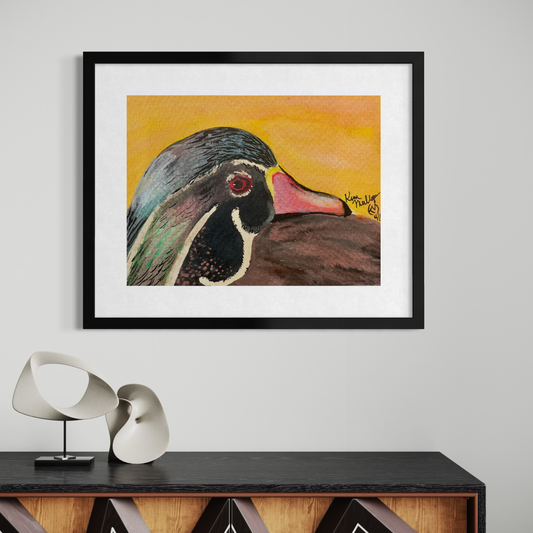 Framed watercolor painting of a duck head on a wall above a console table with decorative items.